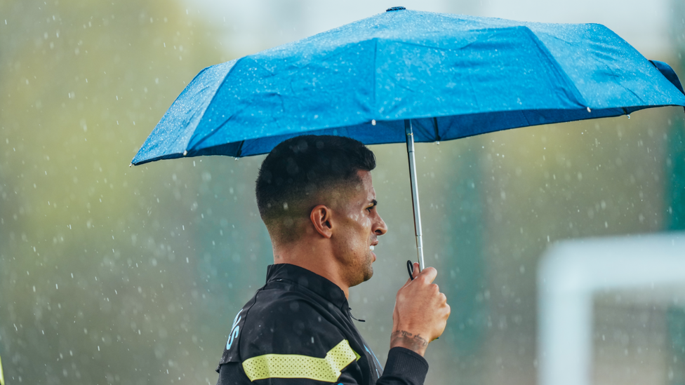 RAIN MAN: Joao Cancelo gets a spot of shelter via a trusty blue umbrella!