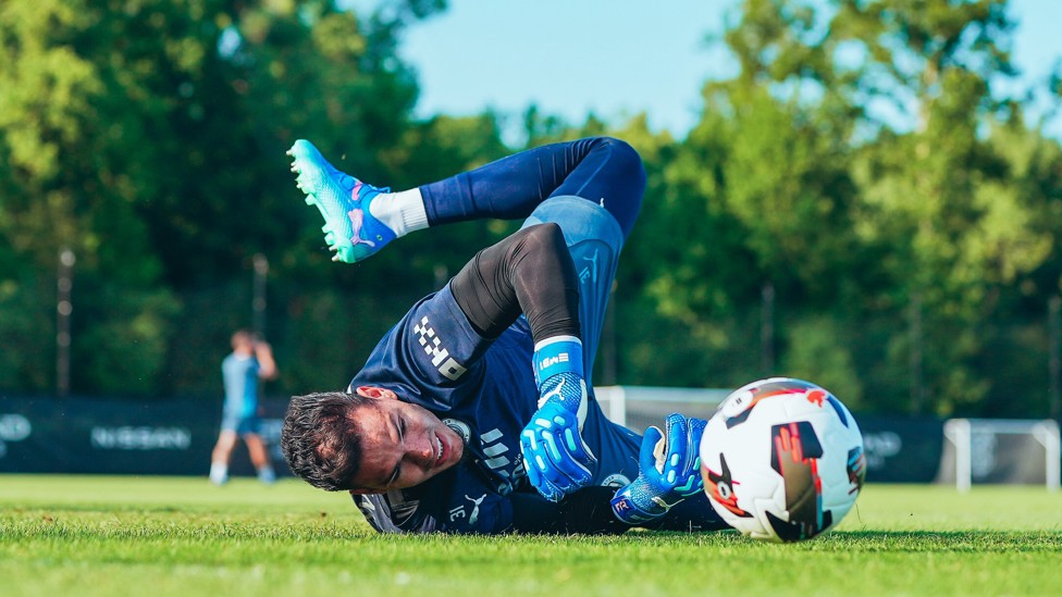 SUPER SAVE  : Ederson gets down to his right.