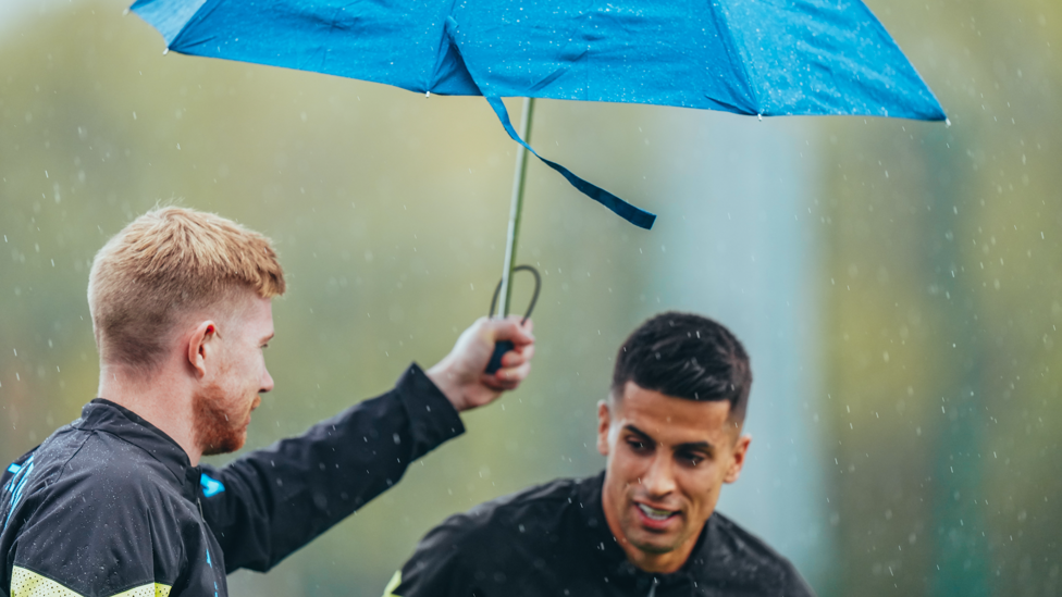 BROLLYWOOD: Kevin De Bruyne and Joao Cancelo share a spot of shelter