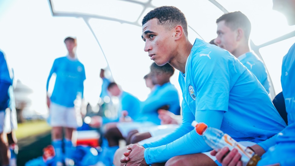 IN THE DUGOUT : Ezra Carrington stays focused in the Under-18s game against Stoke