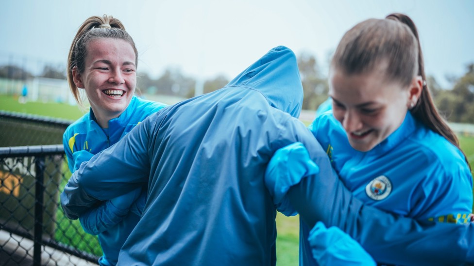 HUDDLE FOR WARMTH : Lauren Hemp and Jess Park are hugged by a mystery figure