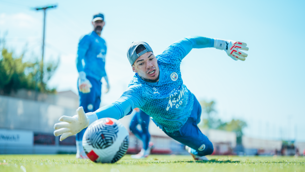 REFLEXES : Ederson gets down to save a shot