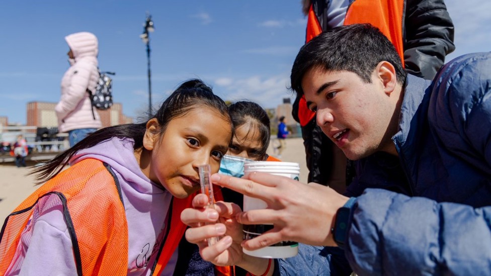 Participants enjoy water testing on Coney Island, NYC, after taking part in a beach football and WASH session.