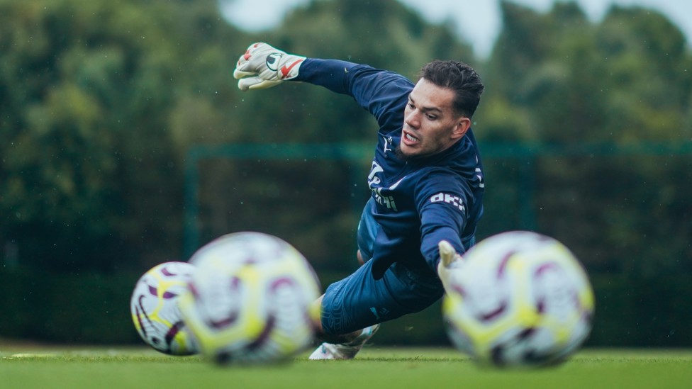 SAFE HANDS  : Ederson makes a save down to his left. 