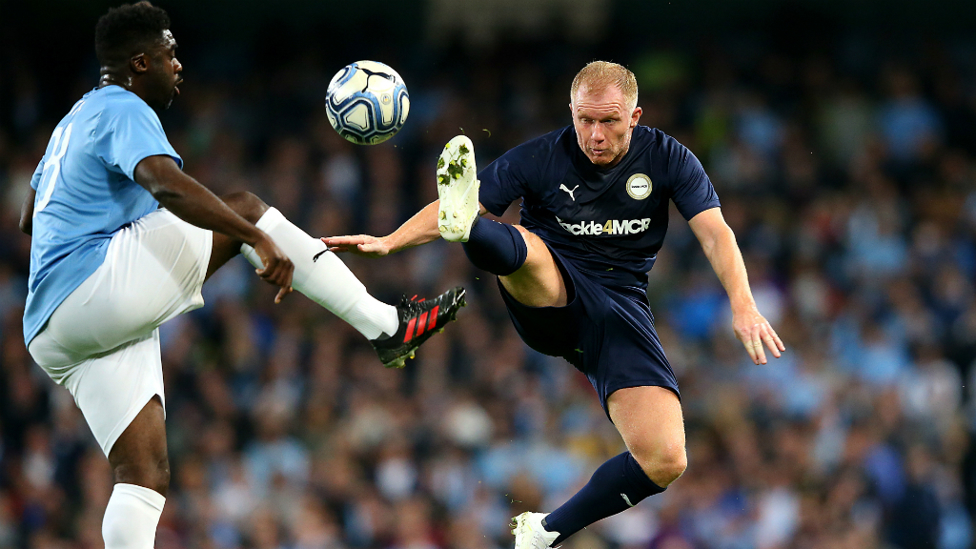 AERIAL BATTLE : Kolo Toure leaps alongside Paul Scholes to win possession